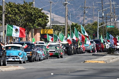El Grito of 2025 with a lineup of classic cars with Mexican flags.