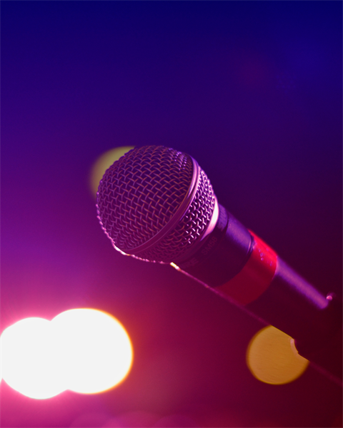 Stock photo of a microphone with concert lights in the background