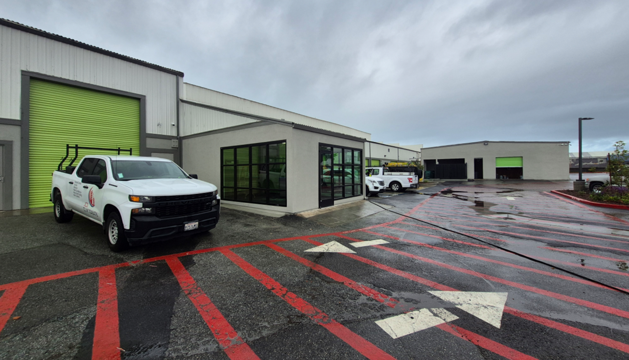 Renovated storage facility at Bridge Street with new office windows, green roll-up doors, and City of Salinas vehicle parked outside.