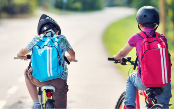Kids riding in a bicycle with backpacks
