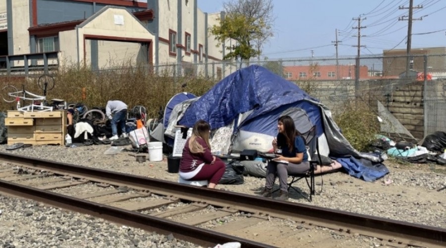 People sitting on the side of railway track Connecting the unhoused community in encampments to services and resources