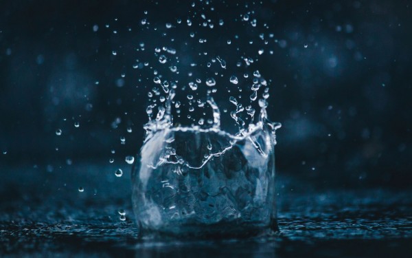 Close-up of a large water splash and droplets on a dark blue background.